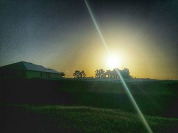 Scenic view of grassy field against sky at sunset