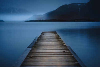 Pier over lake against sky at dusk