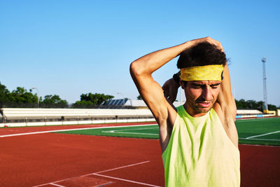 Young man practices stretching on the grass after his daily training