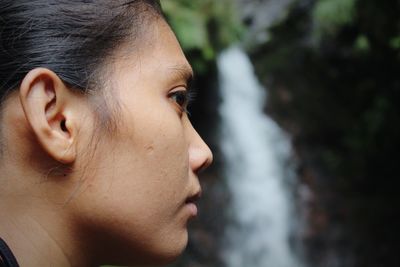 Close-up portrait of woman in front of waterfall 