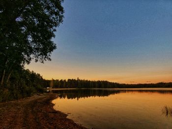 Scenic view of lake against clear sky at sunset