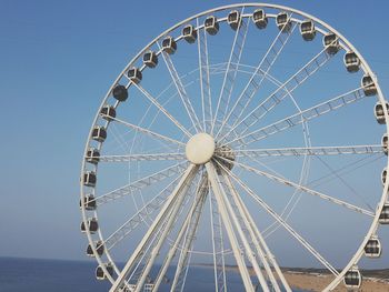 Low angle view of ferris wheel against clear blue sky