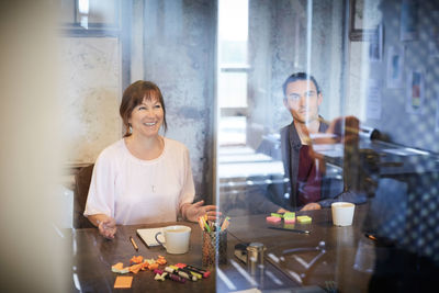 Creative business people sitting in board room seen through glass