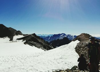 Rear view of woman standing on snowcapped mountain against clear sky