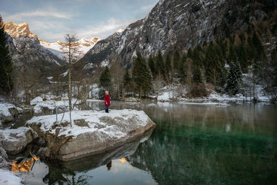 Full length of woman standing on rock by lake against mountain 