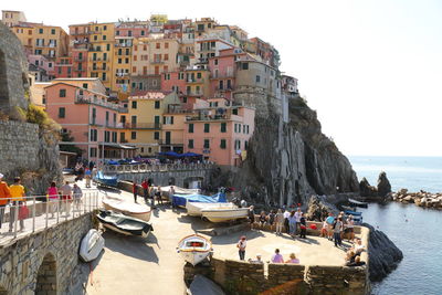 Boats moored in sea by buildings against clear sky