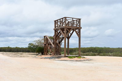 Lifeguard hut on sand against sky