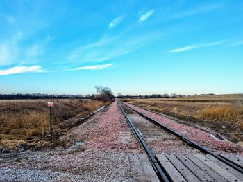 Empty railroad tracks on field against sky