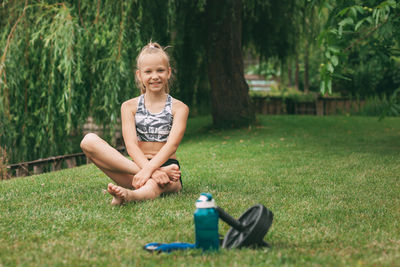 Happy girl sitting on grass against plants