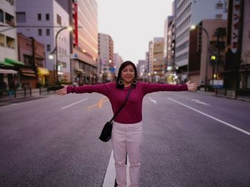 Portrait of young woman standing on road in city