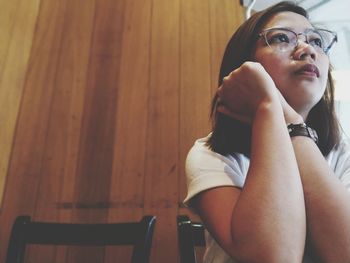 Low angle view of thoughtful young woman looking away at home