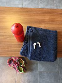 High angle view of towel with bottle and wireless earphones on table