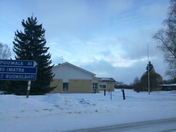 Houses by trees against sky during winter