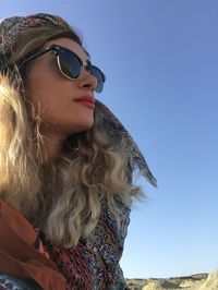 Low angle view of young woman looking away against clear sky
