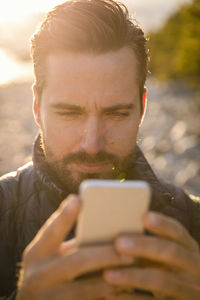 Close-up of man using mobile phone at beach