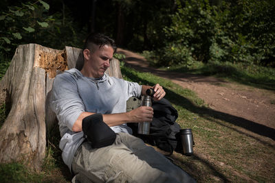 Young man looking at camera while sitting on tree