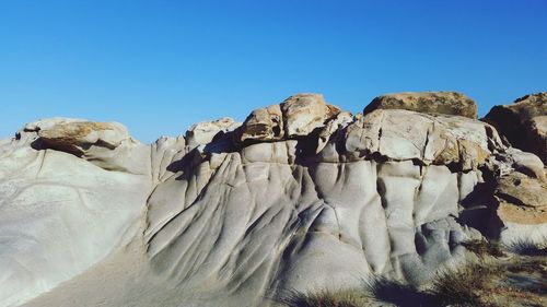 Low angle view of sheep on rock against clear sky