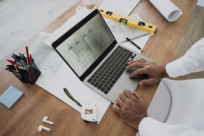 Hands of architect using laptop at desk in office