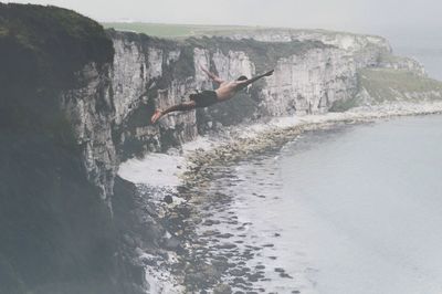 Man jumping on sea against sky