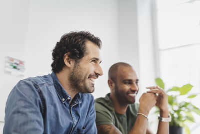 Smiling friends sitting against wall at language class