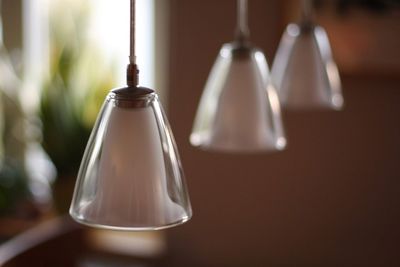 Close-up of pendant lights hanging against wall in room