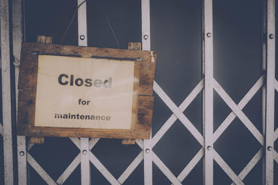 Close-up of text hanging on metal against sky