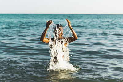 Man splashing water in sea against sky