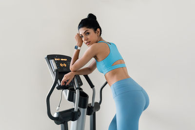 Young woman training at the gym using eliptical crosstrainer