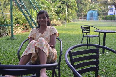 Portrait of young woman wearing nightie sitting chair at yard