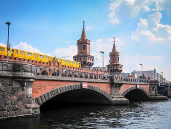 Arch bridge over river in city against sky