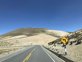 Road sign against clear blue sky