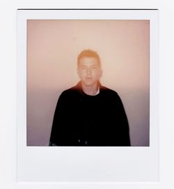 Portrait of young woman standing against white wall