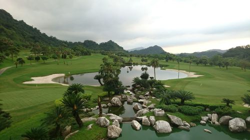 Scenic view of lake and grassy field against cloudy sky