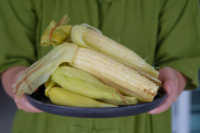 Midsection of person holding boiled corn