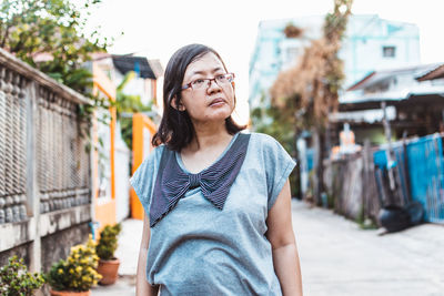 Portrait of woman standing against buildings in city