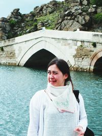 Woman standing against bridge at riverbank