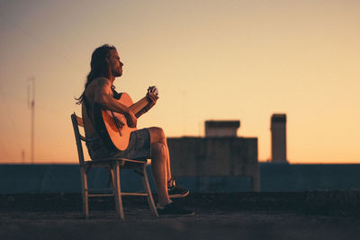 Young man playing accousting guitar on rooftop