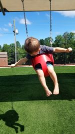 Boy playing on swing in playground