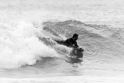 Man surfing in sea against sky
