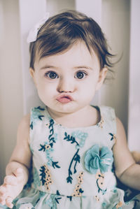 Portrait of cute baby girl puckering lips while sitting at home