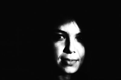 Close-up portrait of young woman over black background