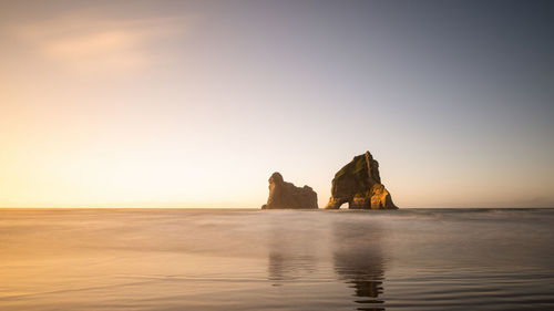 Scenic view of rock formation in sea against clear sky