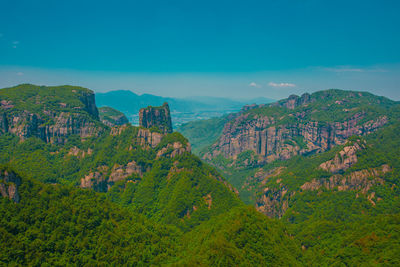 Scenic view of trees and mountains against blue sky