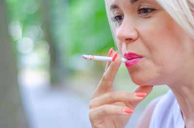 Intriguing photo of blonde who smokes. lighted cigarette in awoman's hand.