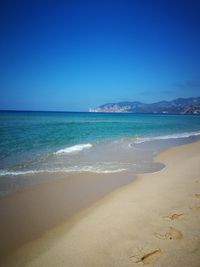 Scenic view of beach against clear blue sky