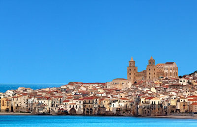 Buildings at waterfront against blue sky