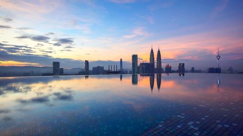 Scenic view of sea and buildings against sky during sunset