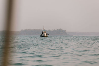 Boat sailing in sea against clear sky