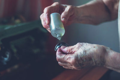 Cropped hands of tailor applying oil on sewing machine part