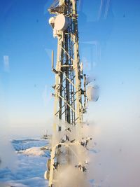 Electricity pylon on snowcapped mountain against blue sky